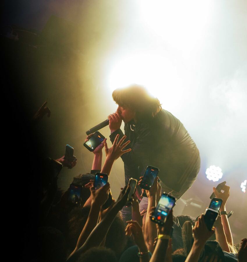 2Slimey leaning over a crowd of fans during a backlit performance